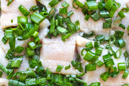 Salted herring fillet with green onions. Salted fish close-up.