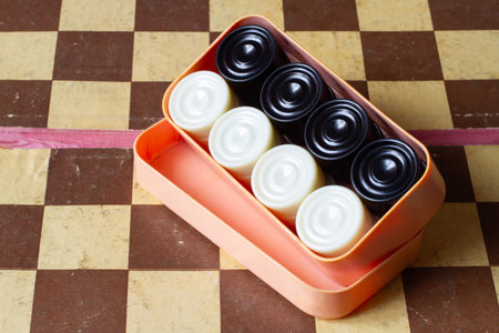 A box with a set of old checkers against the background of a chessboard. Vintage checkers setの写真素材