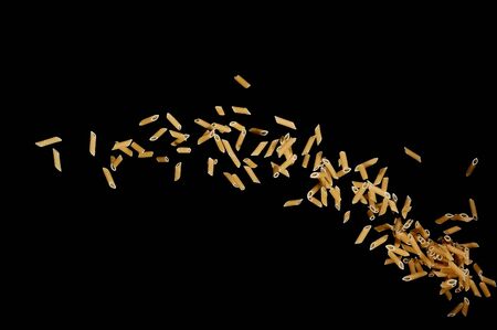 Flying pasta isolated on black background. Abstract macaroni falling.の写真素材