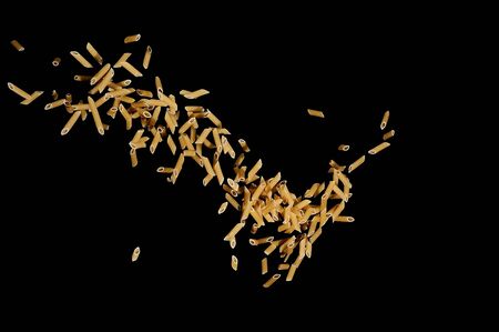 Flying pasta isolated on black background. Abstract macaroni falling.の写真素材