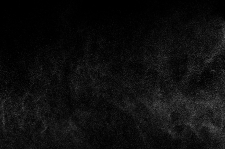 Abstract splashes of water on black background. Freeze motion of white particles. Rain, snow texture.の写真素材