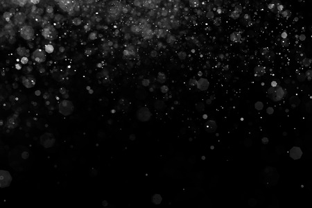 Abstract splashes of water on black background. Freeze motion of white particles. Rain, snow overlay texture.の写真素材