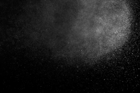 Abstract splashes of water on black background. Freeze motion of white particles. Rain, snow overlay texture.の写真素材