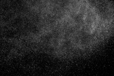 Abstract splashes of water on black background. Freeze motion of white particles. Rain, snow overlay texture.の写真素材