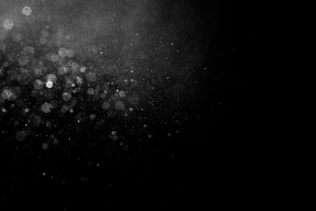 Abstract splashes of water on black background. Freeze motion of white particles. Rain, snow overlay texture.の写真素材