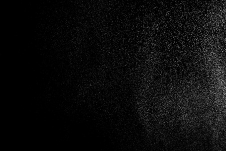 Abstract splashes of water on black background. Freeze motion of white particles. Rain, snow overlay texture.の写真素材