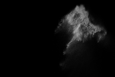 Freeze motion of white particles on black background. Powder explosion. Abstract dust overlay texture.の写真素材