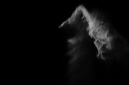 Freeze motion of white particles on black background. Powder explosion. Abstract dust overlay texture.の写真素材