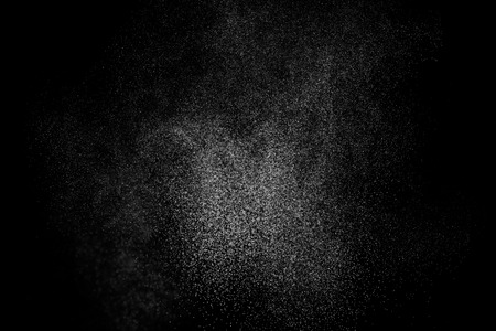 Abstract splashes of water on black background. Freeze motion of white particles. Rain, snow overlay texture.の写真素材
