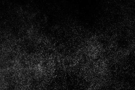 Abstract splashes of water on black background. Freeze motion of white particles. Rain, snow overlay texture.の写真素材