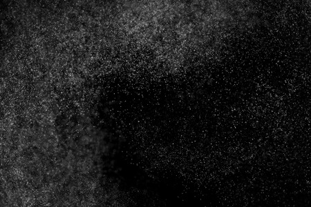 Abstract splashes of water on black background. Freeze motion of white particles. Rain, snow overlay texture.の写真素材