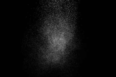 Abstract splashes of water on black background. Freeze motion of white particles. Rain, snow overlay texture.の写真素材