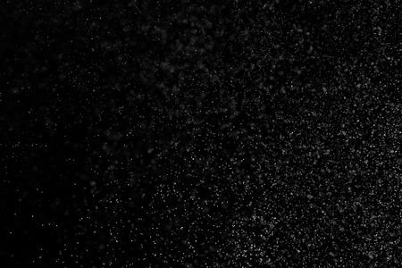 Abstract splashes of water on black background. Freeze motion of white particles. Rain, snow overlay texture.の写真素材