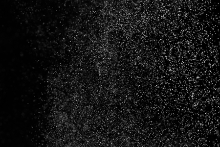 Abstract splashes of water on black background. Freeze motion of white particles. Rain, snow overlay texture.の写真素材