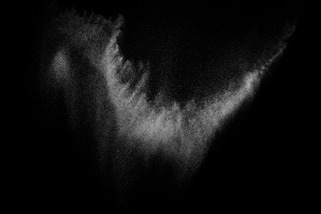 Freeze motion of white particles on black background. Powder explosion. Abstract dust overlay texture.の写真素材