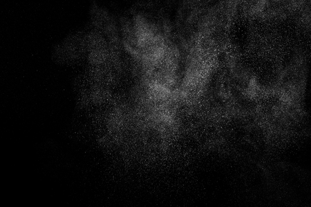 Freeze motion of white particles on black background. Powder explosion. Abstract dust overlay texture.の写真素材
