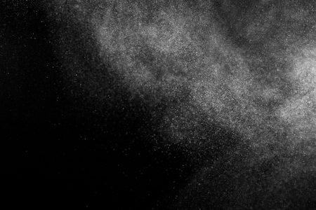 Freeze motion of white particles on black background. Powder explosion. Abstract dust overlay texture.の写真素材