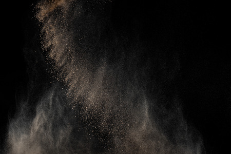 Soil explosion isolated on black background. Abstract cloud of brown ground.