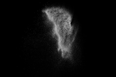 Freeze motion of white particles on black background. Powder explosion. Abstract dust overlay texture.の写真素材