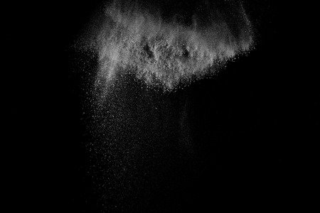 Freeze motion of white particles on black background. Powder explosion. Abstract dust overlay texture.の写真素材