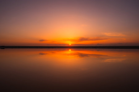 Sunset or sunrise sky. Clouds over water. Golden Dawn. Dramatic coast nature background. Beautiful sea beach at sunset. Morning shoreline sunlight.の写真素材