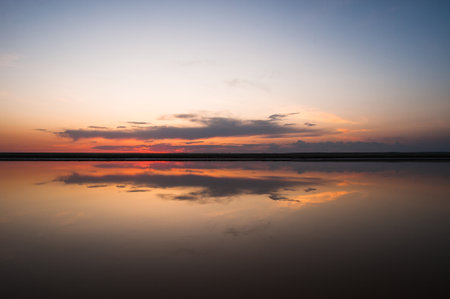 Sunset or sunrise sky. Clouds over water. Golden Dawn. Dramatic coast nature background. Beautiful sea beach at sunset. Morning shoreline sunlight.の写真素材