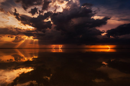 Thunderous dark sky. Black clouds and thunderstorm lightning. Concept on the theme stormy, thunderbolt, thunder, rain. Dramatic skies over the water landscape. Nature background.の写真素材
