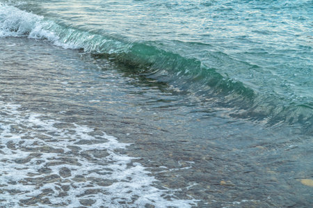 Sea waves on the pebble beach. Blue sea surface with waves. Abstract background of water flow in ocean, sea, river, lake. Seascape wallpaper.の写真素材