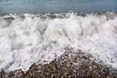 Sea waves on the pebble beach. Blue sea surface with waves. Abstract background of water flow in ocean, sea, river, lake. Seascape wallpaper.の写真素材