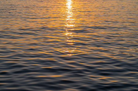 Water sea sunset. Sun reflection ocean waves. Nature golden abstract texture surface.の写真素材