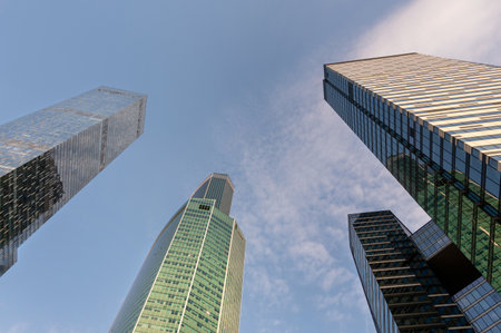 Angled view of modern skyscrapers in business district against blue sky. Looking Up high-rise office...
