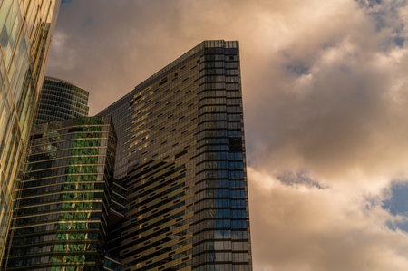 Skyscrapers in business district against blue sky. Looking up high-rise office buildings. Evening time, sunset. Orange, yellow and gold shades of color. Angled view.の写真素材