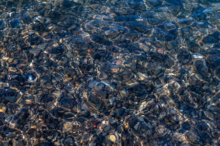 Underwater pebble backgrounds. Colorful stones sea bottom in the sun rays. View from above through clear water. Seascape wallpaper texture. Defocus.の写真素材