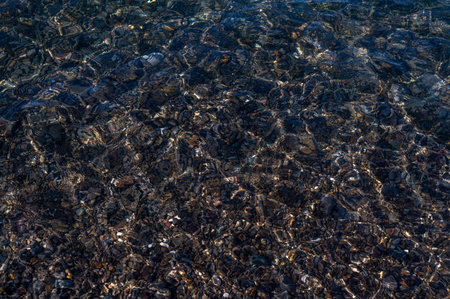 Underwater pebble backgrounds. Colorful stones sea bottom in the sun rays. View from above through clear water. Seascape wallpaper texture. Defocus.の写真素材
