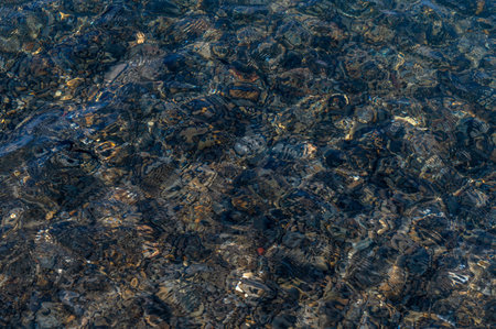Underwater pebble backgrounds. Colorful stones sea bottom in the sun rays. View from above through clear water. Seascape wallpaper texture. Defocus.の写真素材
