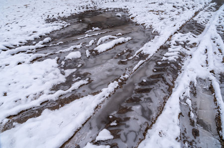 Tire tracks in the ice mud of winter in rural with snow. Off-road in frozen land. Landscape nature background.の写真素材