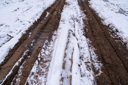 Tire tracks in the ice mud of winter in rural with snow. Off-road in frozen land. Landscape nature background.の写真素材