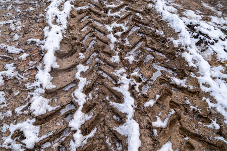 Tire tracks in the ice mud of winter in rural with snow. Off-road in frozen land. Landscape nature background.の写真素材