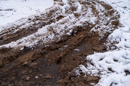 Tire tracks in the ice mud of winter in rural with snow. Off-road in frozen land. Landscape nature background.の写真素材