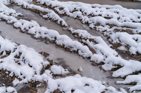 Tire tracks in the ice mud of winter in rural with snow. Off-road in frozen land. Landscape nature background.の写真素材