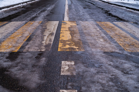 Cross walk empty covered with ice and snow. Pedestrian crossing slippery. Dirty asphalt road background. Crosswalk top view. Road surfaces and highways.の写真素材