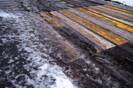Cross walk empty covered with ice and snow. Pedestrian crossing slippery. Dirty asphalt road background. Crosswalk top view. Road surfaces and highways.の写真素材