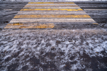 Cross walk empty covered with ice and snow. Pedestrian crossing slippery. Dirty asphalt road background. Crosswalk top view. Road surfaces and highways.の写真素材