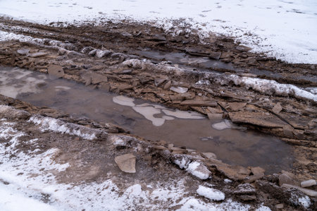 Tire tracks in the ice mud of winter in rural with snow. Off-road in frozen land. Landscape nature background.の写真素材