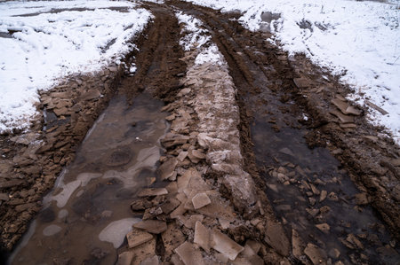 Tire tracks in the ice mud of winter in rural with snow. Off-road in frozen land. Landscape nature background.の写真素材