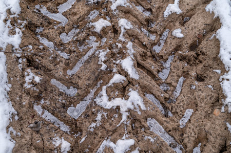 Tire tracks in the ice mud of winter in rural with snow. Off-road in frozen land. Landscape nature background.の写真素材