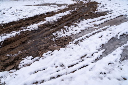 Tire tracks in the ice mud of winter in rural with snow. Off-road in frozen land. Landscape nature background.の写真素材