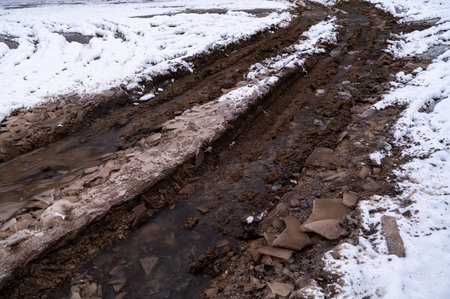 Tire tracks in the ice mud of winter in rural with snow. Off-road in frozen land. Landscape nature background.の写真素材