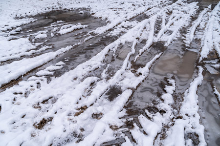 Tire tracks in the ice mud of winter in rural with snow. Off-road in frozen land. Landscape nature background.の写真素材