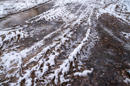 Tire tracks in the ice mud of winter in rural with snow. Off-road in frozen land. Landscape nature background.の写真素材
